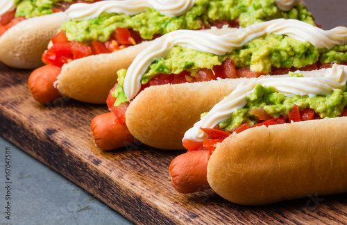 Chilean Completo Italiano. Hot dog sandwiches with tomato, avocado and mayonnaise on wooden board. closeup photo