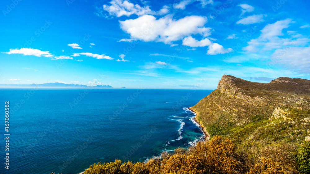 The rugged coast of the Atlantic Ocean and wind swept peaks on the Cape Peninsula in South Africa with Cape Agulhus, the most southerly point of the African Continent in the distant