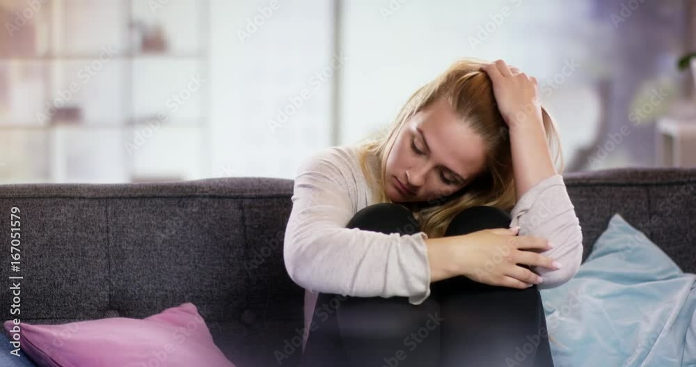 Sad young woman sitting on the couch holding her arms in front of her