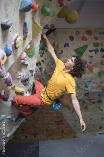 Rock climber bouldering intdoors on climbing wall