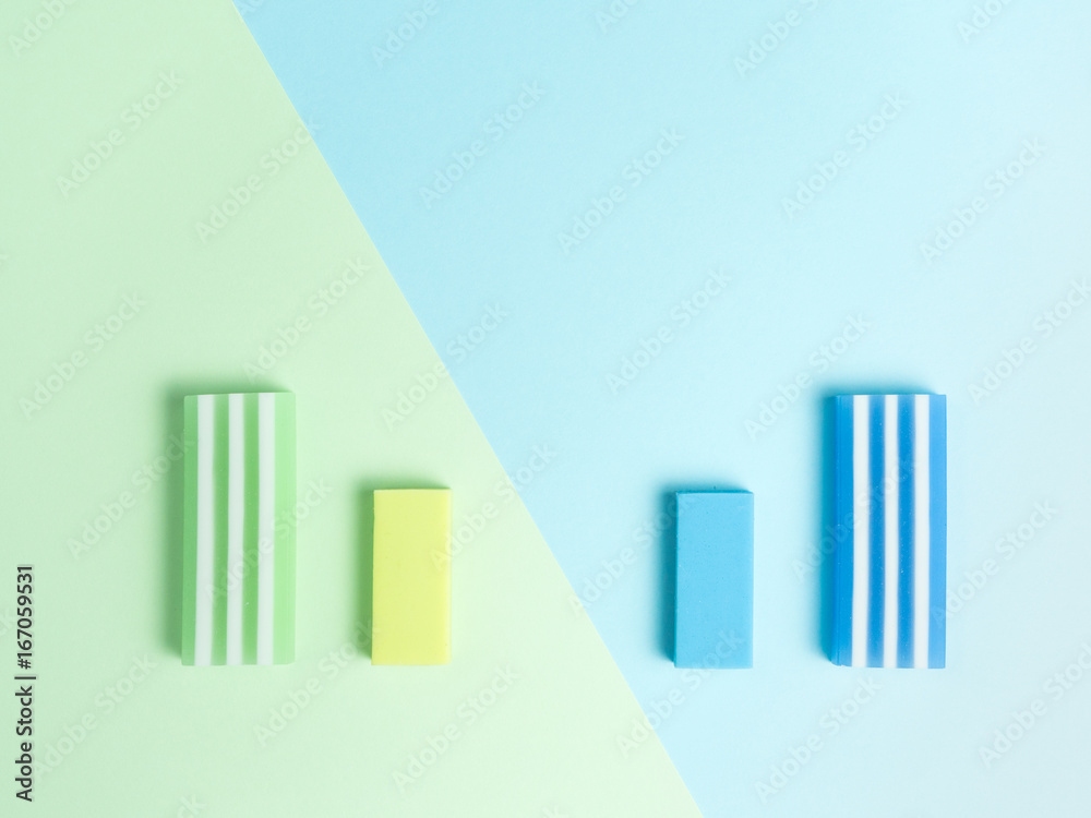 big and little green eraser and blue eraser on green and light blue background. big and little green eraser and blue eraser on green and light blue background.
