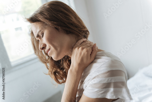 Gloomy cheerless woman touching her neck photo