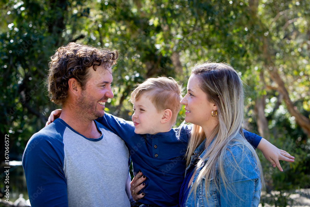 Father, Mother and young son together outdoors in sunlight in park Father, Mother and young son together outdoors in sunlight in park