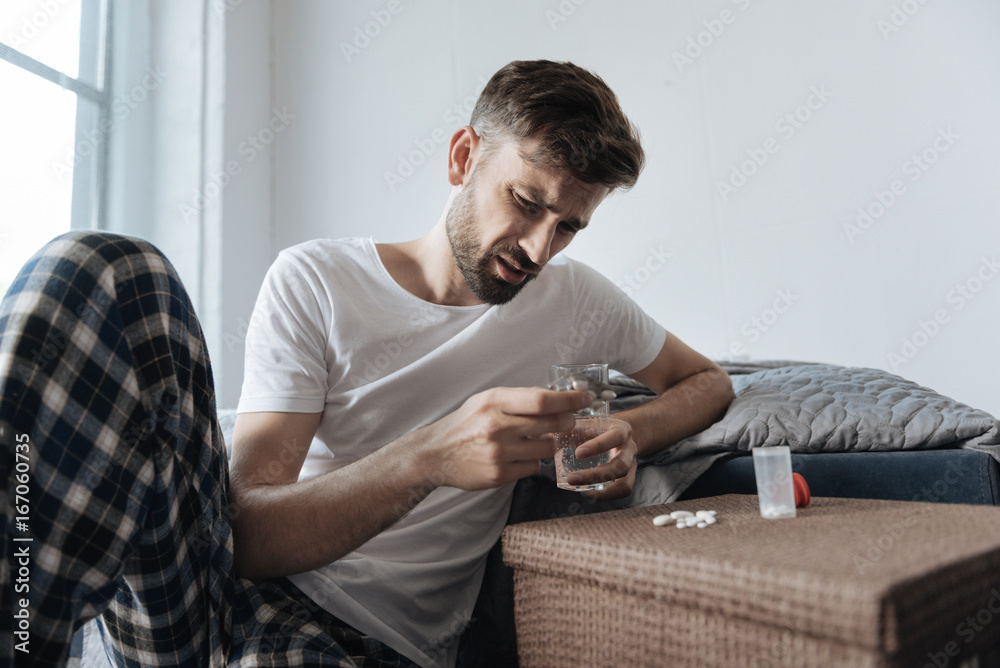 Depressed cheerless man taking medicine Depressed cheerless man taking medicine