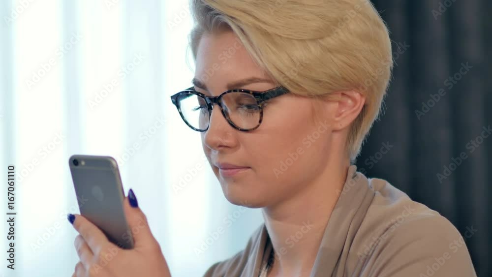 Charming joyful female is reading pleasant text message on mobile phone from her boyfriend during her rest time Charming joyful female is reading pleasant text message on mobile phone from her boyfriend during her rest time