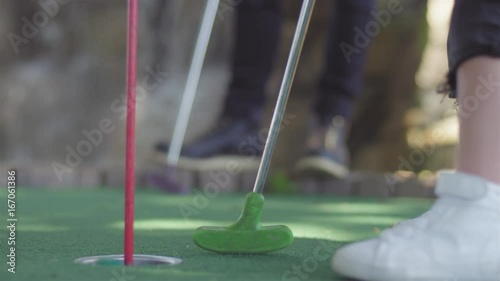 Small child putting a golf ball in a hole at a putt putt golf course photo