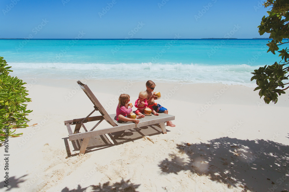 little boy and two girls drinking coconut on beach