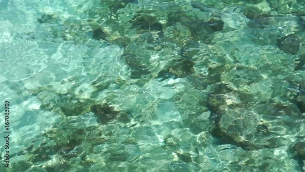 Top View of crystal clear ocean waves with rocks on sand bottom Top View of crystal clear ocean waves with rocks on sand bottom