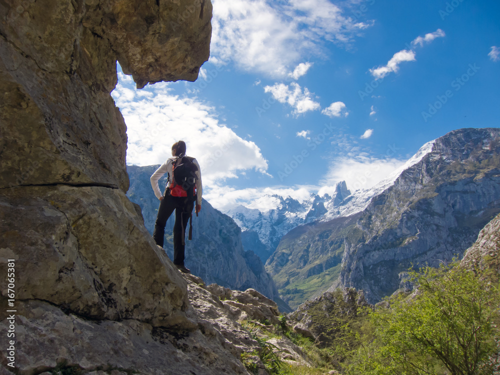 Woman hiker with backpack watching spectacular mountain landscape in Picos de Europa, Asturias, Spain