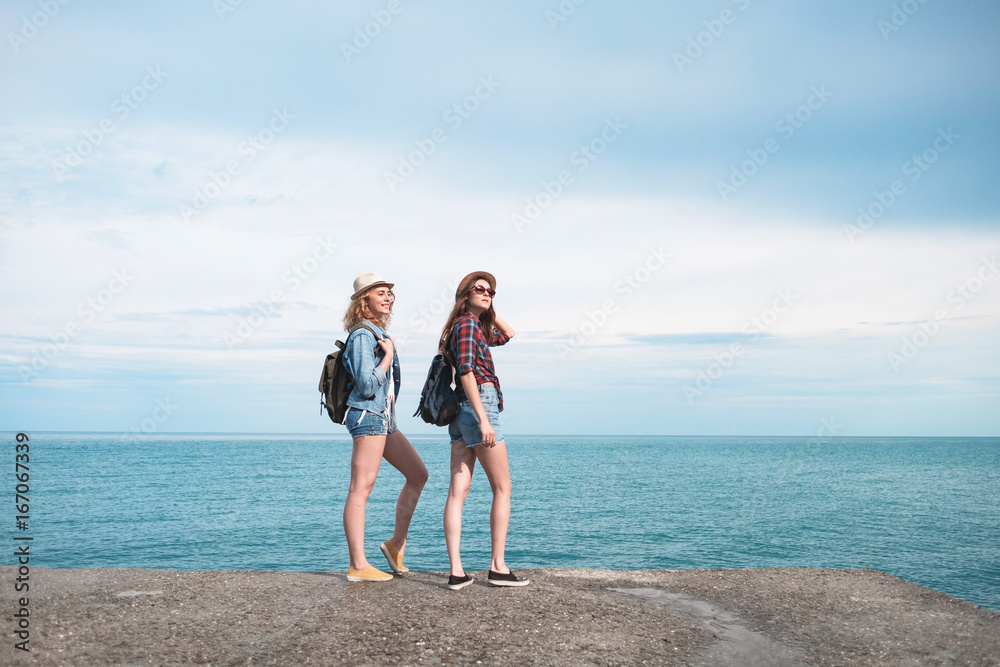 Two girls are traveling along the seashore Two girls are traveling along the seashore