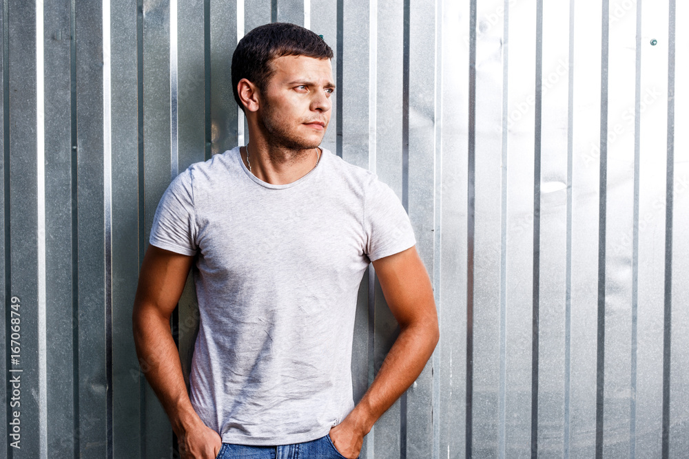 Outdoor portrait of a handsome young man in jeans and gray t-shirt. Outdoor portrait of a handsome young man in jeans and gray t-shirt.