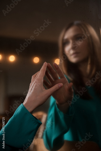 Young woman touching her own reflection in a mirror