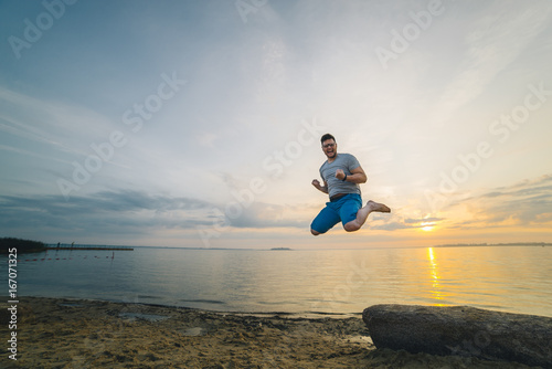 man jump on the beach with sunrise on background photo