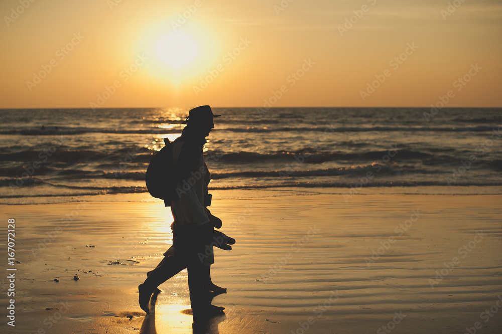 People walk along the sea at sunset. Sunset on sea. Silhouette of people. Walking by the sea. Travelers at sunset. Tourists on vacation People walk along the sea at sunset. Sunset on sea. Silhouette of people. Walking by the sea. Travelers at sunset. Tourists on vacation