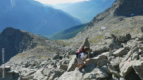 Woman climbing on high altitude rocky mountain cliff. Summer adventures on the Italian French Alps