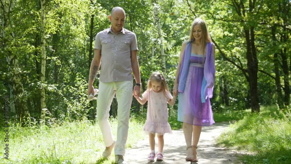 Family - mammy, daddy and daughter - walking in park at summer day Family - mammy, daddy and daughter - walking in park at summer day