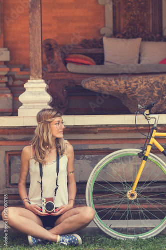 Pretty woman sitting with old bicycle outdoors.