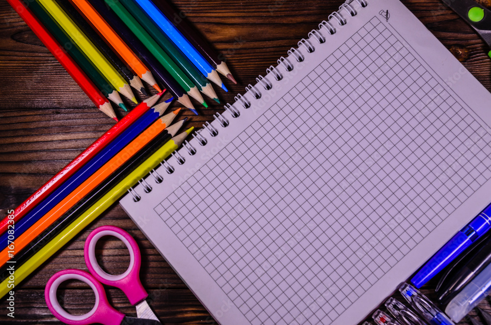Set of different school stationeries. Notepad, scissors, pensils, on wooden desk. Back to school. Top view Set of different school stationeries. Notepad, scissors, pensils, on wooden desk. Back to school. Top view