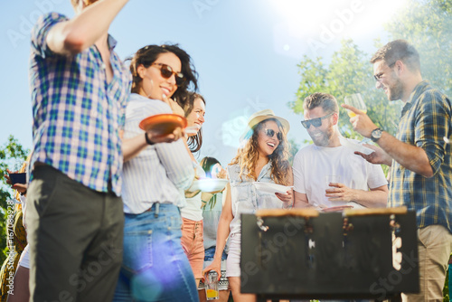 Small group of people standing around barbecue grill at outdoor party