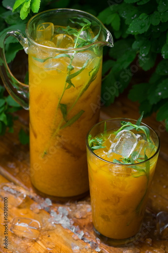 Citrus lemonade with herbs on a wooden background. Orange lemonade with tarragon. close up