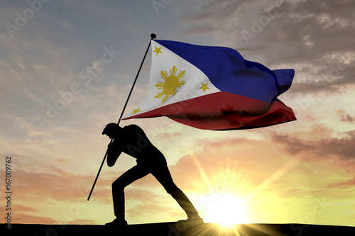 Philippines flag being pushed into the ground by a male silhouette. 3D Rendering