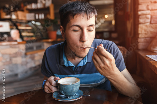 Young man enjoying coffee with piece of cake in cafe