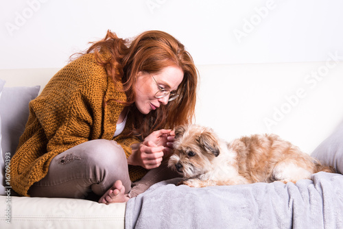 schöne, rothaarige Frau mit ihrem Hund auf der Couch