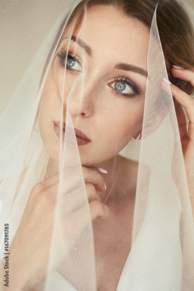 Fototapeta premium Stunning bride with deep blue eyes under the veil