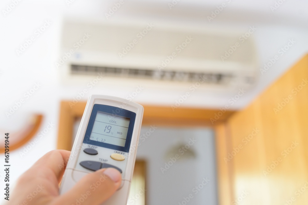 Hand adjusting temperature of home air conditioner Hand adjusting temperature of home air conditioner