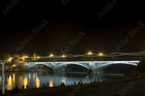 Iluminación nocturna del hermoso puente de Triana en la ciudad de Sevilla, España © Antonio ciero