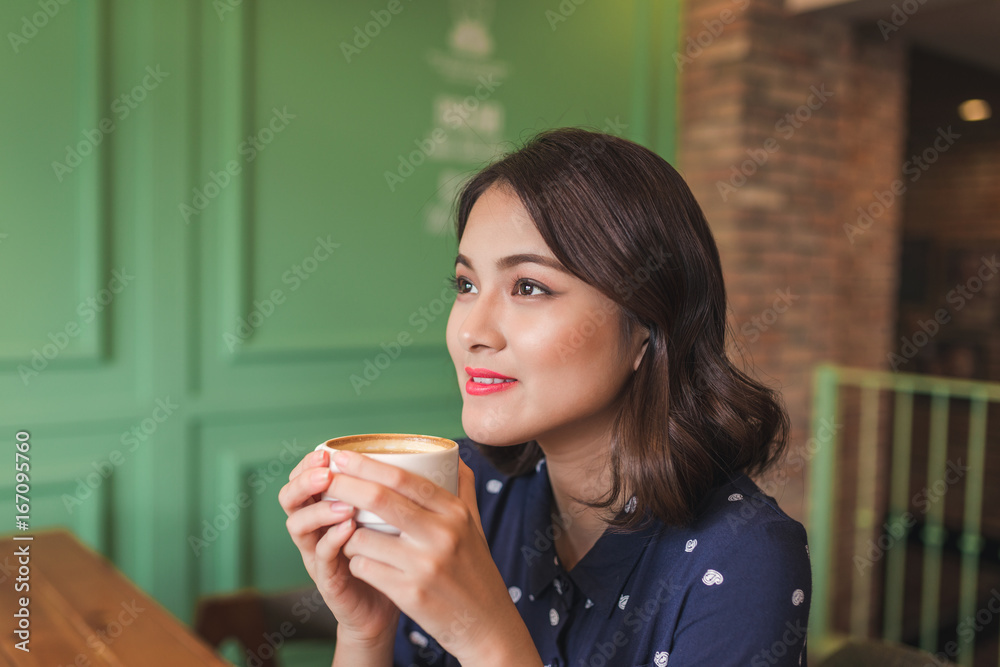 Portrait of happy young business woman with mug in hands drinking coffee in the morning at restaurant Portrait of happy young business woman with mug in hands drinking coffee in the morning at restaurant