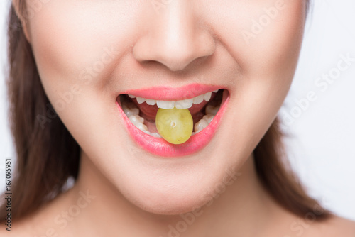 Young beautiful asian woman eating fresh grapes isolated on white background