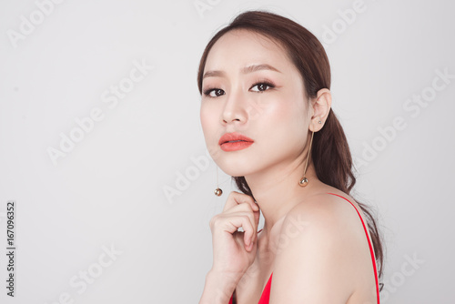 Portrait of stylish asian woman wearing red dress on grey background.