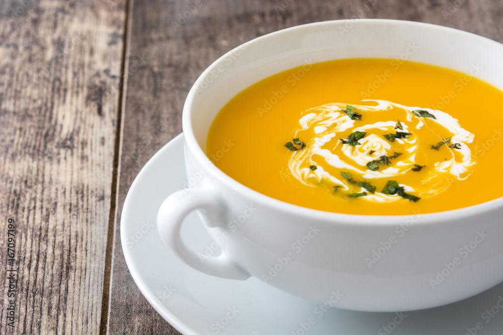 Pumpkin soup in white bowl on wooden table
Pumpkin soup in white bowl on wooden table