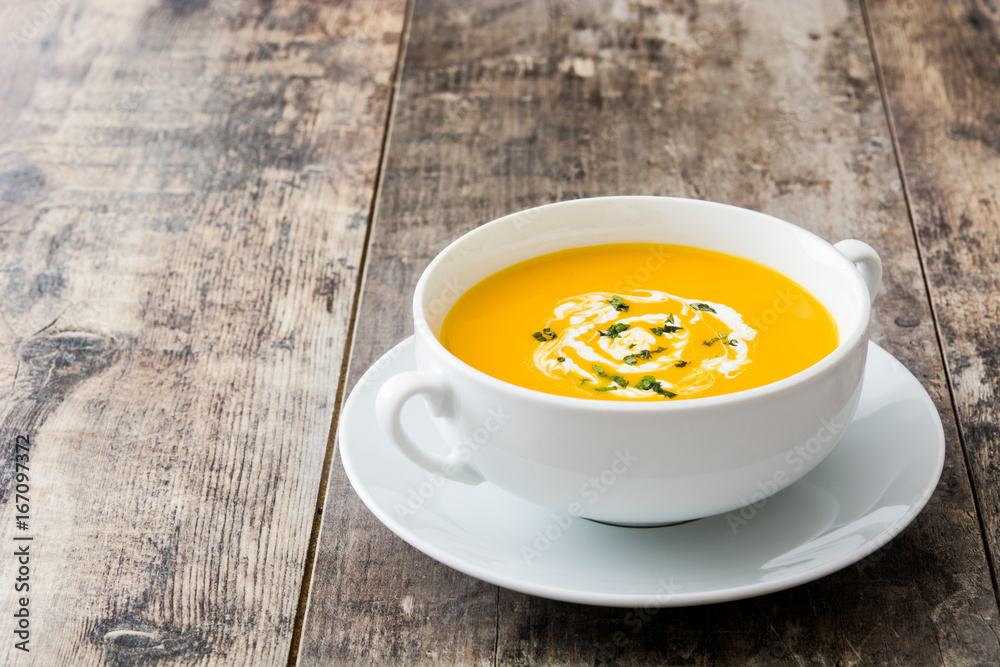 Pumpkin soup in white bowl on wooden table
Pumpkin soup in white bowl on wooden table