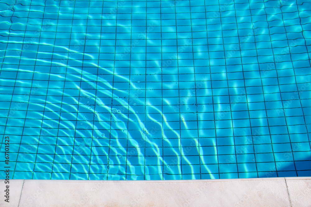 Blue ripped water in swimming pool. Swimming pool bottom caustics ripple and flow with waves background. Clear light blue pool water ripples with sun reflections. Surface of blue swimming pool.
