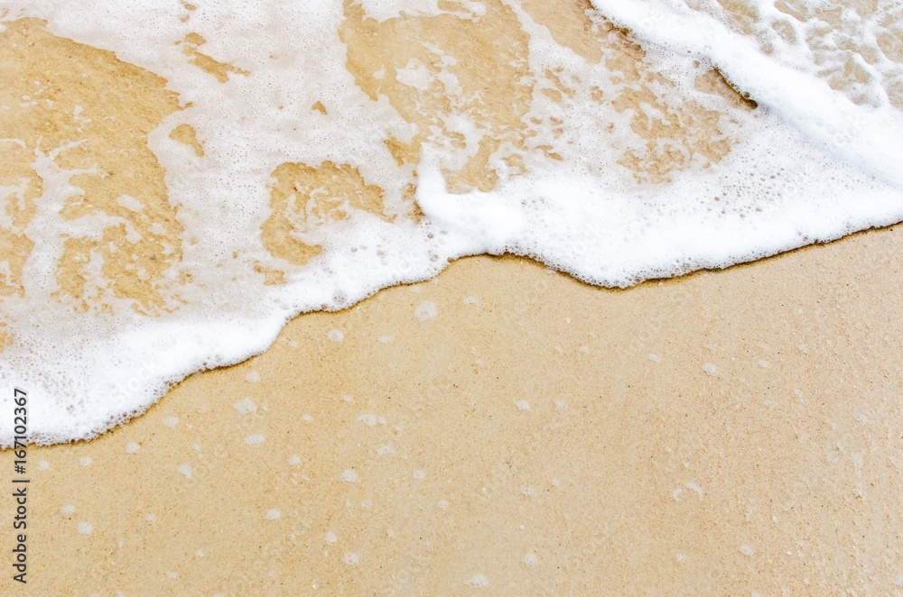 Fototapeta premium top view of soft sea wave on sand at the beach, beach background and summer concept, sunlight effect, copy space