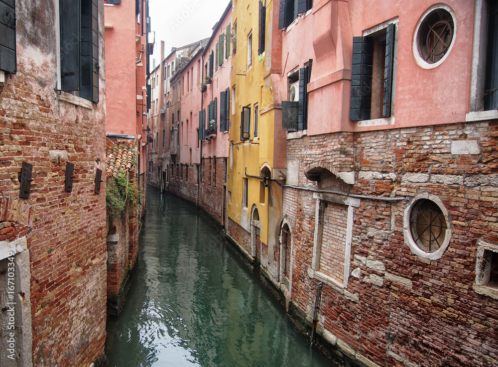 small canal in venice with old buildings balconies a fading painted walls
