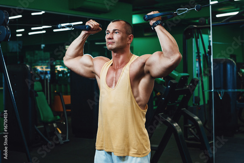 Handsome power athletic man on diet training pumping up back muscles pull up. Strong bodybuilder with six pack, perfect abs, back, shoulders, biceps, triceps and chest photo