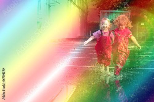 Children play on the street after the rain in pink bright rubber boots. The rays of the sun are reflected in the drops of water