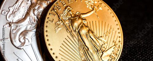 silver eagle and golden american eagle one ounce coins / closeup of silver eagle and golden american eagle one ounce coins on black background photo