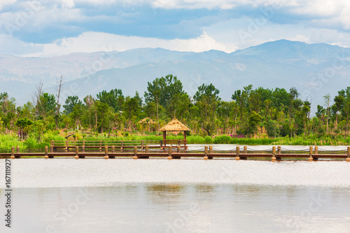 Little wood pavilion on a lake with mountains in the background, Xichang, China