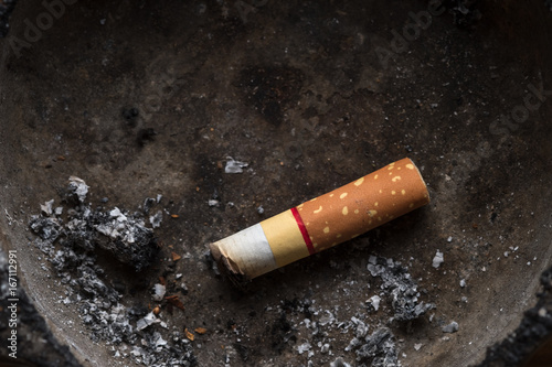 Cigarette / Close up of cigarette in dirty ashtray. Dark tone.