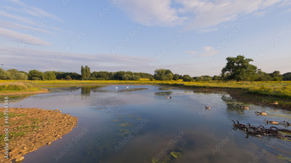 Obraz premium Aerial view over a lake in the summer late afternoon