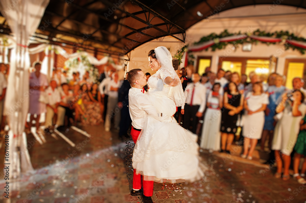 Fantastic wedding couple dancing their first dance in the restaurant with confetti.