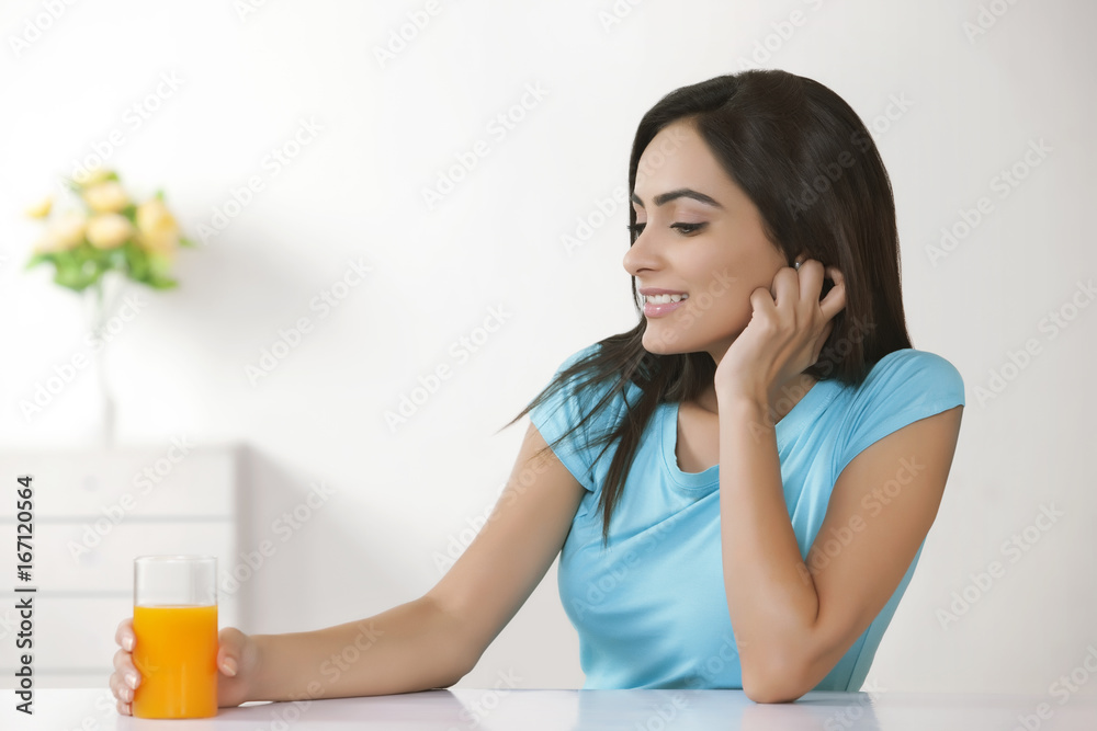 Happy young woman with glass of orange juice at home Happy young woman with glass of orange juice at home