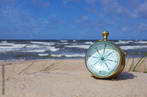 antique brass nautical compass on the beach