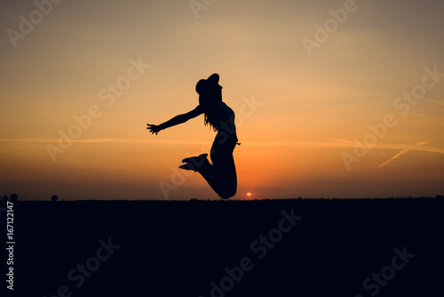 Joyful girl jumping at sunset. Silhouette