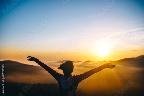 Man, tourist, over clouds in mountains at sunset feels freedom and happy