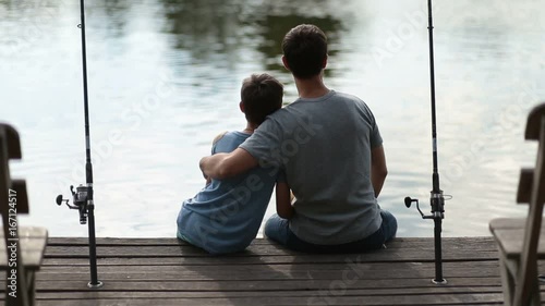 Affectionate father embracing son as they fish